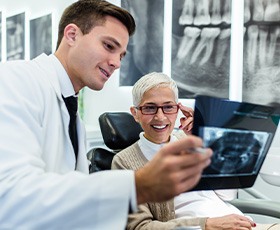 Dentist and patient smiling while looking at X-ray