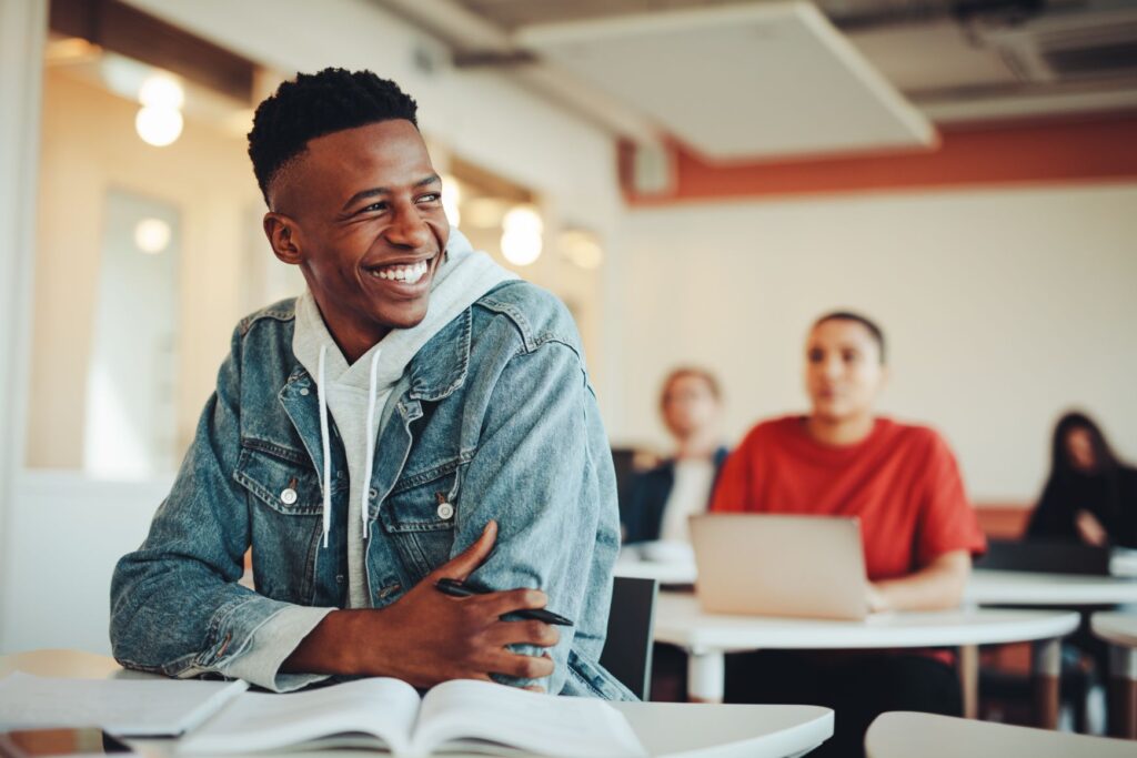 A young man smiling in a classroom.