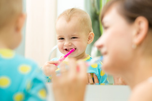 Baby having their teeth brushed by parent